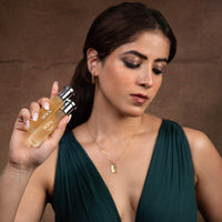 Female model holding Tsar 900Y 20 ml perfume bottle against a brown studio background